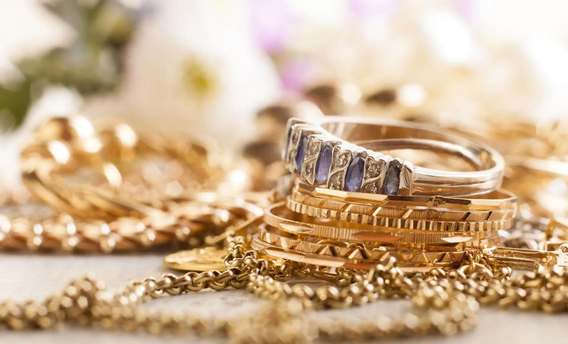 Gold chains, bangles, and a sapphire band ring piled together