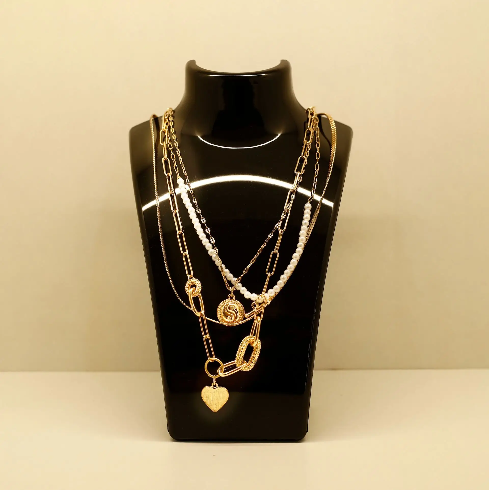 Gold and silver chain necklaces displayed on a black bust