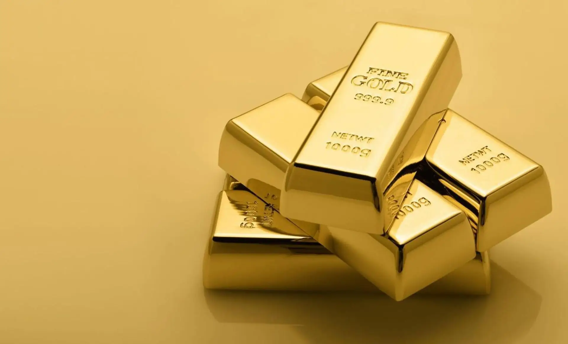 Stacked fine gold bullion bars on a gold background